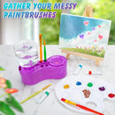 Purple paintbrush holder with brushes, a small easel with a painting, and art supplies on a marble surface.