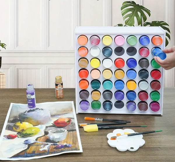 Set of watercolor paints with brushes and a painting on a table