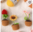 Three crocheted flower pots with yarn balls in the background