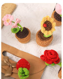 Crocheted flower pots and flowers on a white surface with a brown background