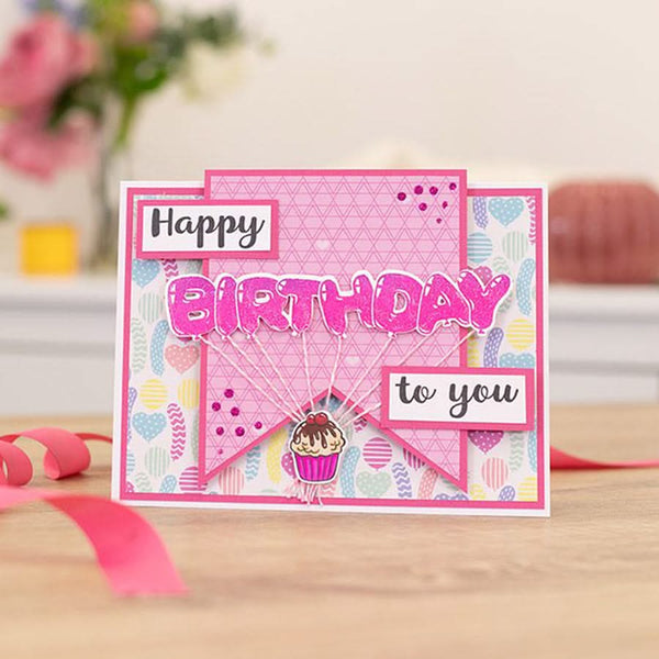 Birthday card with pink and multicolor design on a wooden surface