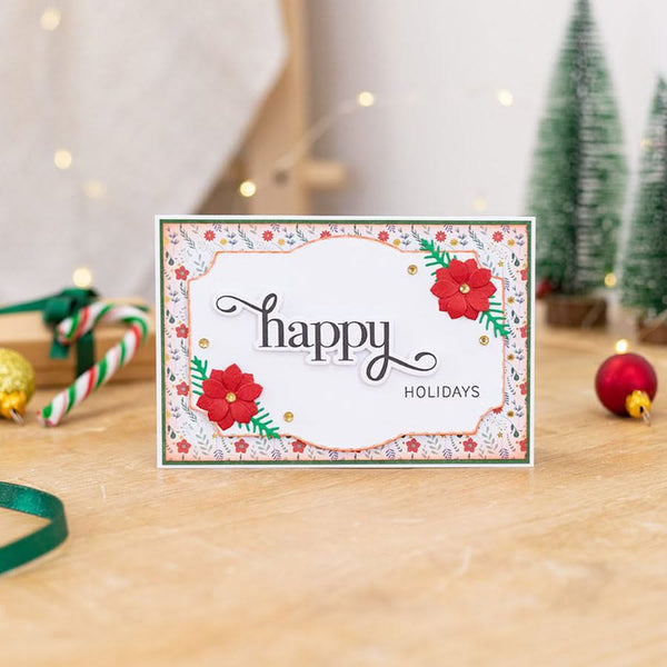 Holiday card with 'happy holidays' text on a wooden surface with Christmas decorations.