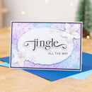 Greeting card with 'jingle all the way' text and floral design on a wooden surface.