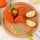 Knitted orange fish and lemon slices on a wooden plate with crochet tools.