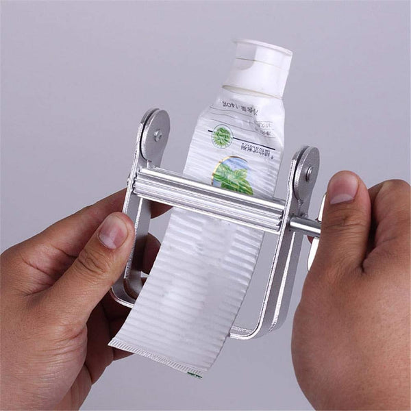 Metallic paper towel holder with a roll of paper towels being pulled out, against a plain background.