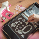 Crafting activity with die-cutting machine and decorative elements on a wooden table.