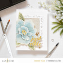 Card with floral design and 'just a note' text on a white surface with stationery items.