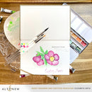 Card with floral design and watercolor supplies on a wooden surface, featuring the brand 'Altenew'.