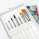 Set of paintbrushes with white handles and silver ferrules in a box, with a painting in the background.
