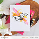 Greeting card with 'GRATEFUL TO YOU' text and autumn leaves on a wooden surface with flowers and stationery.