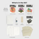 Kit contents including die-cut elements, foam squares, liquid glue, gem sparkles, sentiment strips, A2 card bases, and envelopes on a white background.