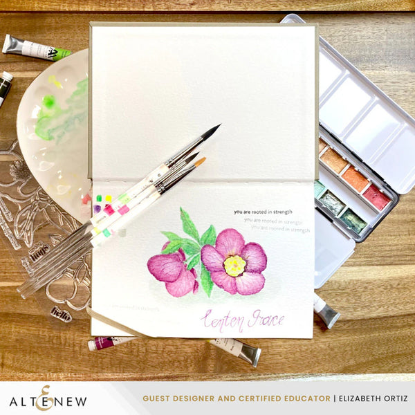 Card with floral design and watercolor supplies on a wooden surface, featuring the brand 'Altenew'.