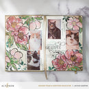 Open book with floral design and cat photos on a marble surface
