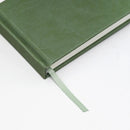Green notebook with a ribbon bookmark on a white background