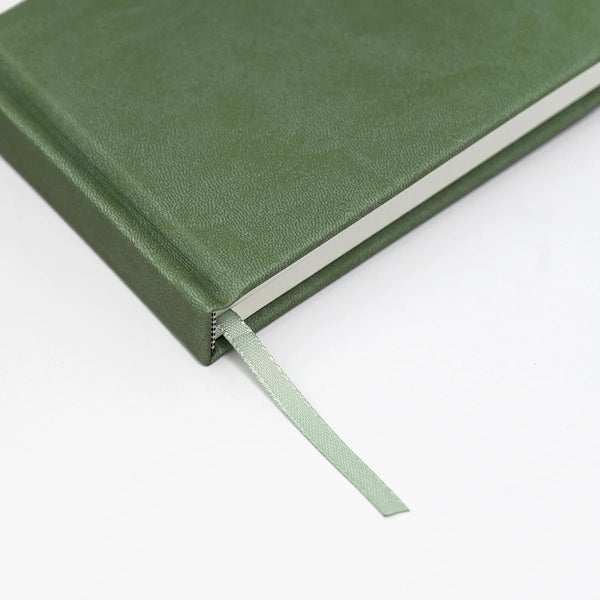 Green notebook with a ribbon bookmark on a white background