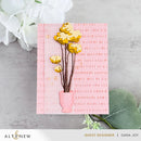 Card with yellow flowers in a pink vase on a textured surface with floral elements.