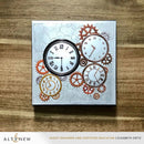 Decorative card with clock designs and gears on a wooden surface, featuring the brand 'Altenew'.