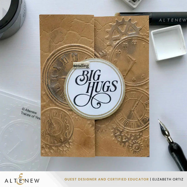 Card with embossed design and 'sending big hugs' text, surrounded by crafting tools on a white background.