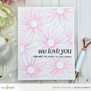Card with pink floral design and 'we love you' text on a wooden surface.