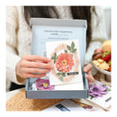 Handmade greeting card with floral design in a box, held by a person.