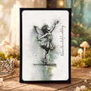 Framed artwork of a fairy dancing with text on a wooden surface with a blurred natural background