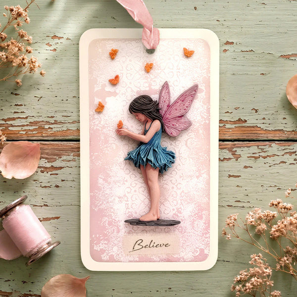 Card with a fairy holding a butterfly on a decorative surface with flowers and candles.