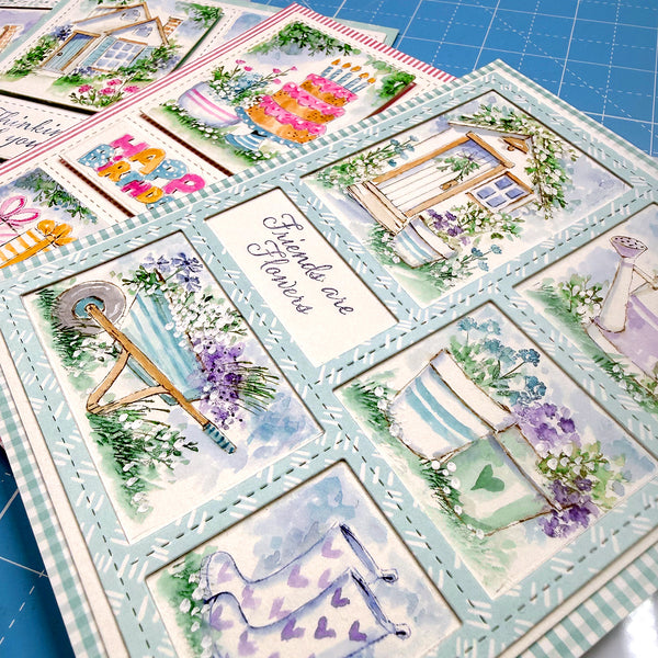 Collection of decorative greeting cards with floral and nature-themed designs on a blue cutting mat.