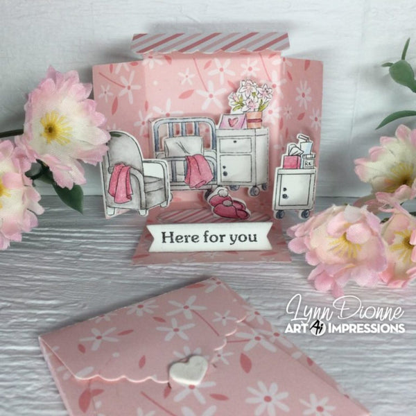 Pink card with illustrations of a hospital room and flowers, featuring the brand 'Lynn Dionne Art Impressions'.