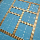 Wooden model kit pieces on a blue cutting mat with grid lines
