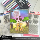 Card with two giraffes and hearts surrounded by craft supplies and stamps on a white surface.