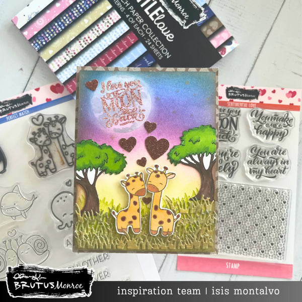 Card with two giraffes and hearts surrounded by craft supplies and stamps on a white surface.