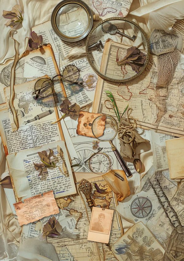 Vintage items including glasses, a compass, and a magnifying glass on top of old maps and papers.