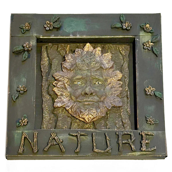 Decorative plaque with a face of a green man and the word 'NATURE' on a white background