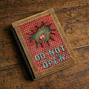 Decorative book with dragon design and 'Do Not Open' text on a wooden surface