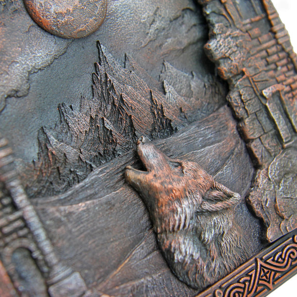 Decorative plaque with a wolf howling at the moon and castle design.