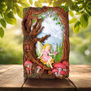 Decorative wall art with fairy and tree design on a wooden surface with greenery in the background.