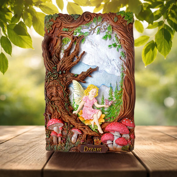 Decorative wall art with fairy and tree design on a wooden surface with greenery in the background.