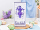 Decorative card with a purple cross and flowers on a table with Easter eggs.
