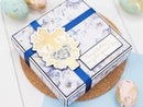 Decorative gift box with floral design and blue ribbon on a light background