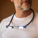 Man wearing a neck-mounted light device on a plain background
