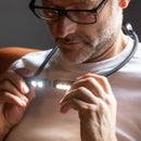 Man adjusting a neck strap on a white shirt against a dark background