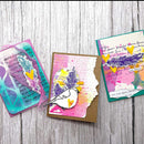 Three colorful greeting cards with feather and heart designs on a wooden surface