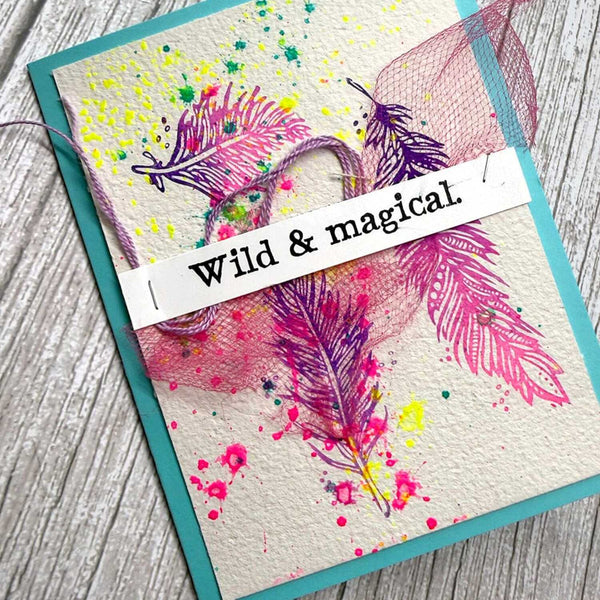 Colorful feather design with 'Wild & Magical' text on a textured surface