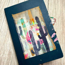 Notebook with a colorful cactus design on a wooden surface