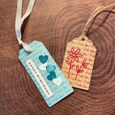 Two decorative gift tags with heart and flower designs on a wooden surface