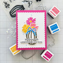 Card with flowers and text on a crafting surface with stamps and tools.