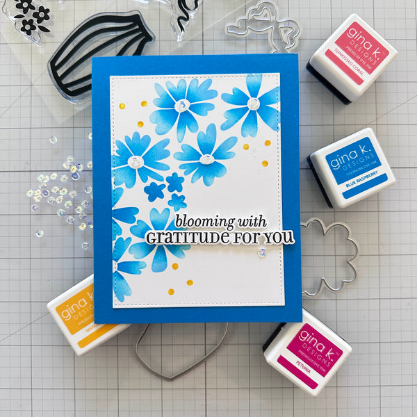 Card with blue floral design and text on a grid background with stamps and tools.