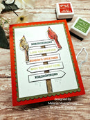 Card with cardinal design and text on a wooden surface with stamps and flowers.