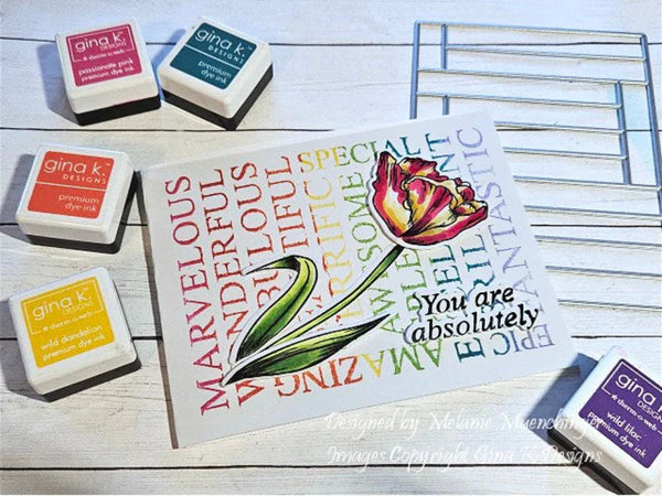 Card with a tulip illustration and赞美 text, surrounded by Gina K. Designs stamps on a wooden surface.