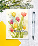 Greeting card with tulips and 'Birthday Wishes' text, pen, and flowers on a textured surface.